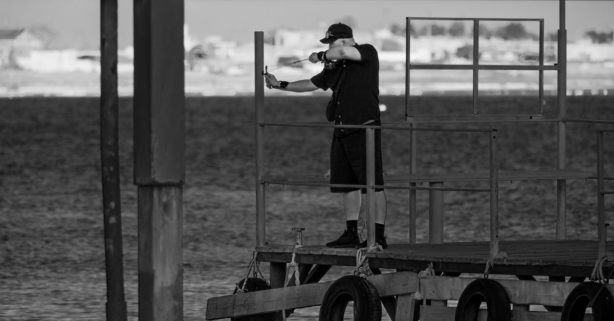 Monochrome image of a man taking a photo on a pier in Aktau, Kazakhstan at the Caspian Sea.